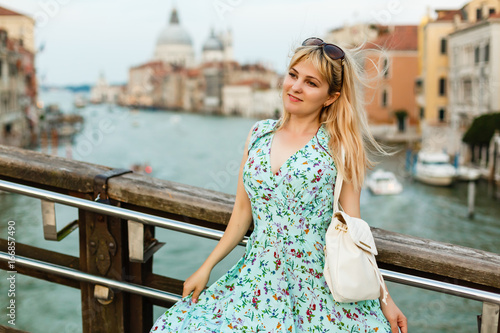 Beautiful well-dressed woman posing on a bridge over the canal in Venice.