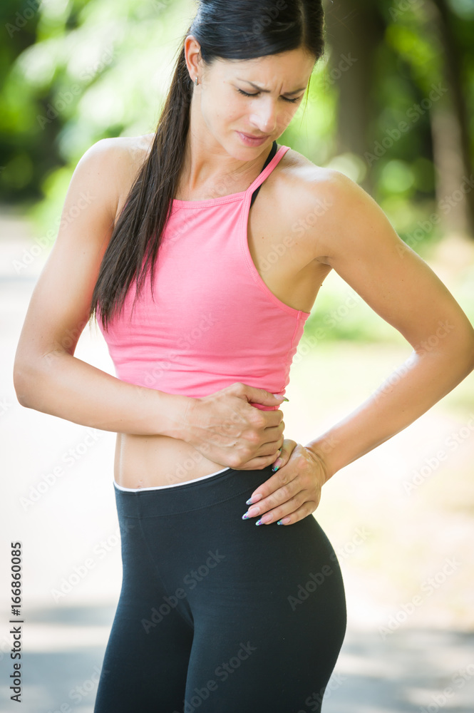 sport woman back pain in a park in summer