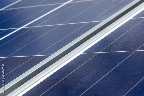 Blue solar panels against background of sky with clouds