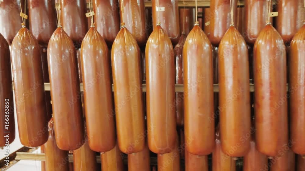 Smoked cheese is suspended on a rope on a metal trolley in the food ...
