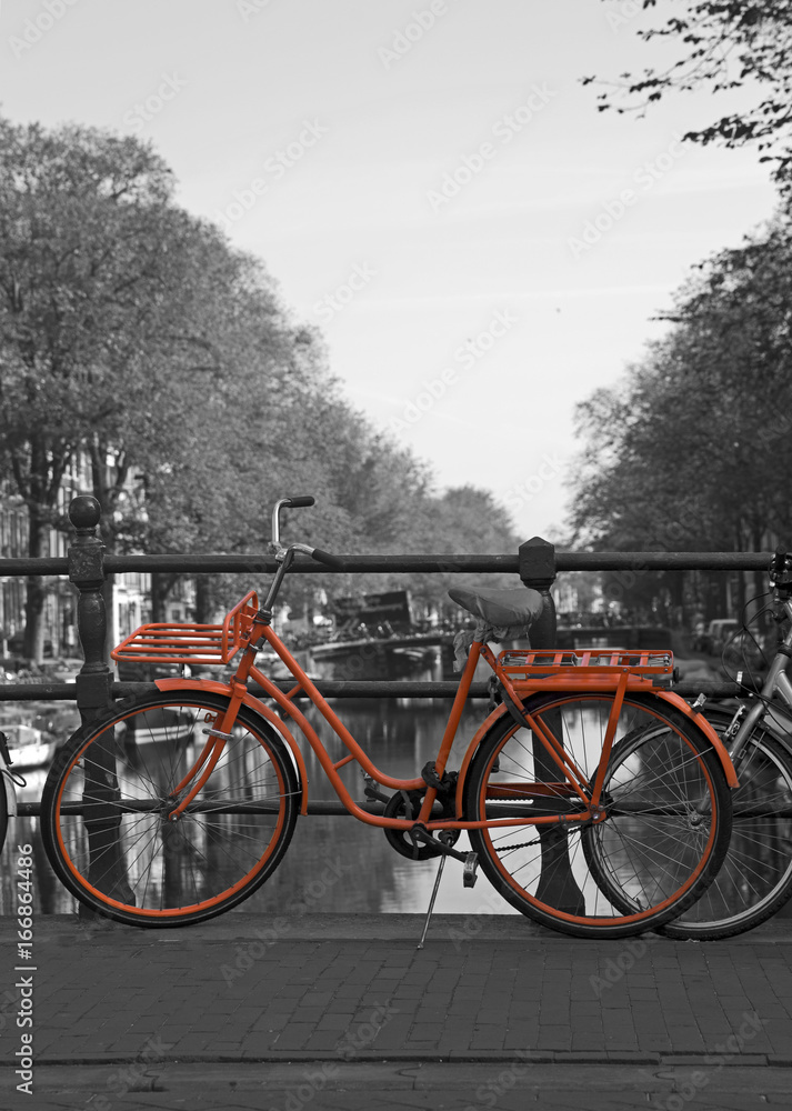 Black and white view of Amsterdam with orange bicycle