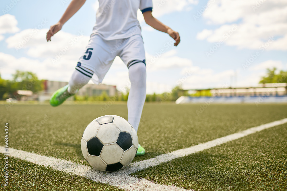 Boy Kicking Ball on Football Field