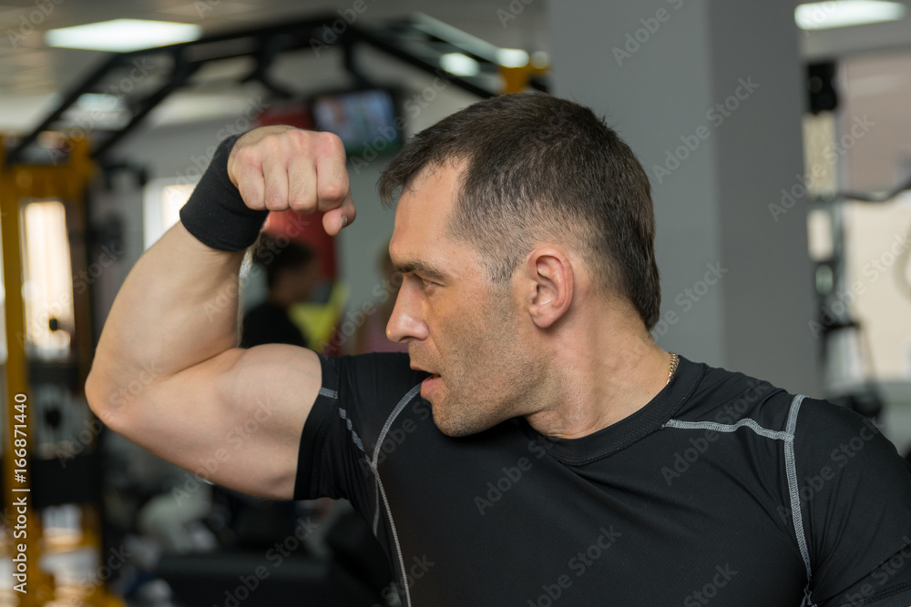 Young muscular man showing his biceps in gym Young muscular man showing his biceps in gym
