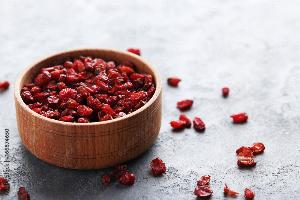Pile of dry barberries in bowl on grey wooden table Pile of dry barberries in bowl on grey wooden table