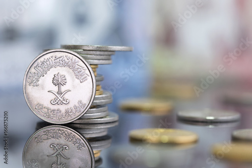 Saudi Riyal pounds with a golden one on a reflective surface photo