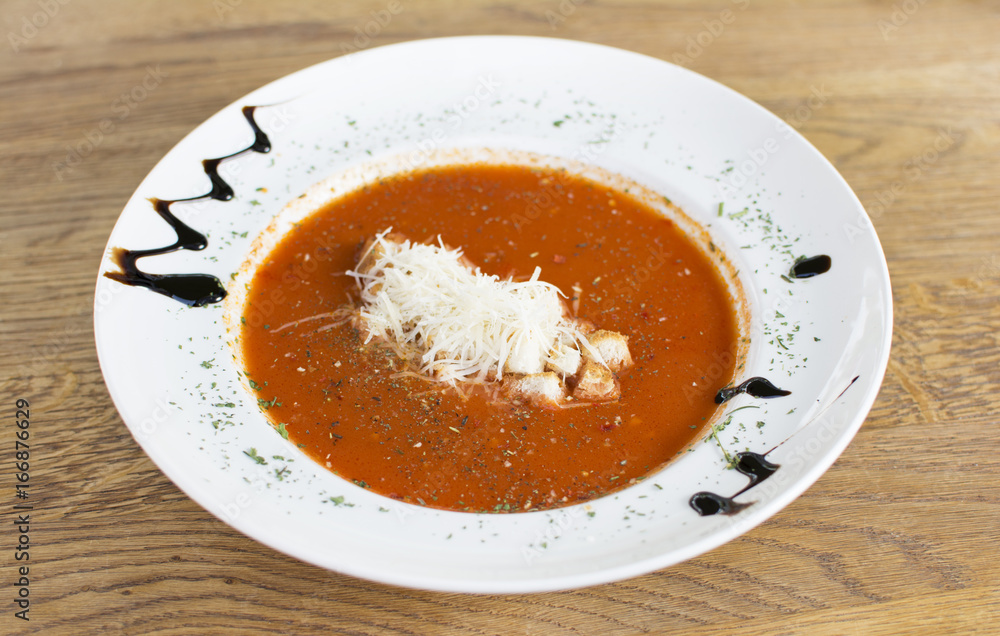 Tomato soup in a black bowl on wooden table. Top view. Tomato soup in a black bowl on wooden table. Top view.