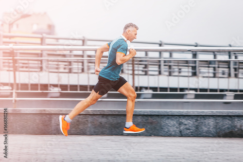 healthy lifestyle middle aged man runner running upstairs on city bridge road. vintage color