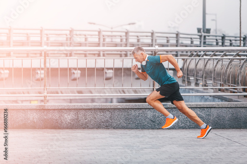healthy lifestyle middle aged man runner running upstairs on city bridge road. vintage color