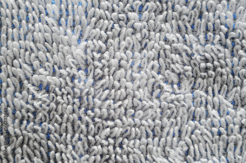 Macro shot of a white towel. Texture is similar to the texture of a fleecy knotted-pile carpet. Chaotically directed white villi on a blue basis