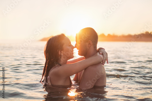Foto Couple in water at sea, hugging, at sunset, golden hour