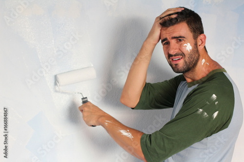 Stressed out male painting his home with space for copy