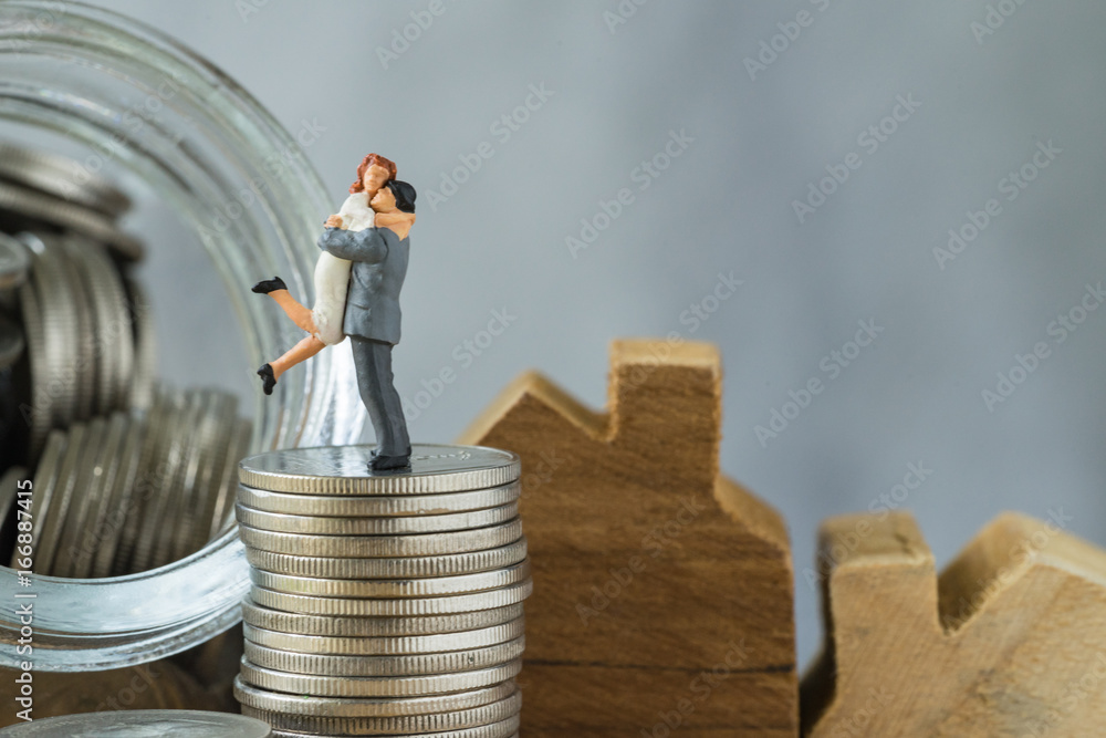 Miniature happy couple family standing on stack of coins as property or financial mortgage plan concept Miniature happy couple family standing on stack of coins as property or financial mortgage plan concept