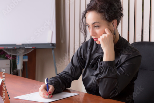 Business woman writing on a paper.