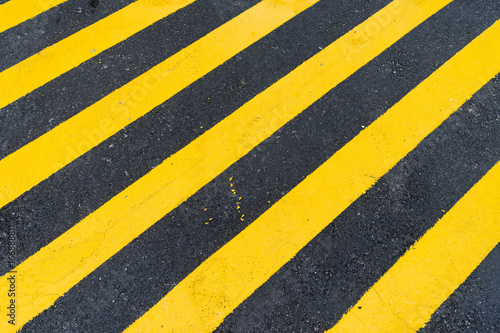 Asphalt Background with diagonal black and yellow warning stripes © Nawadoln