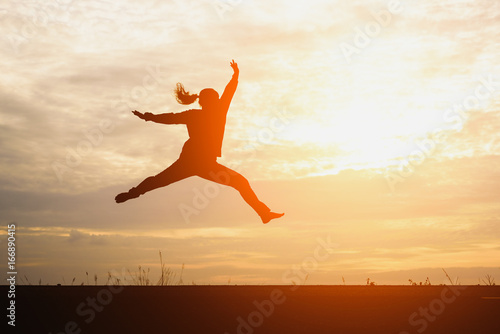 A silhouette of man jumping in the sunset background.