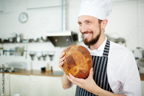 Happy bakery chef with loaf of crusty fresh bread