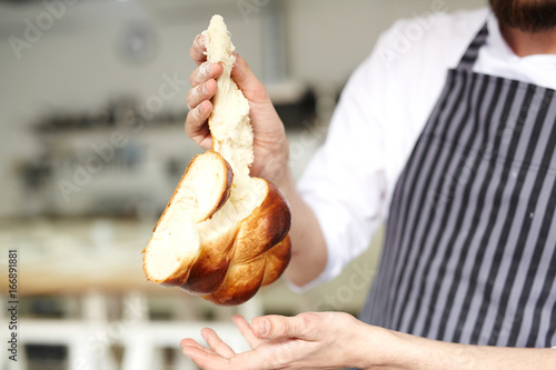 Fresh bread with crust in hands of baker photo