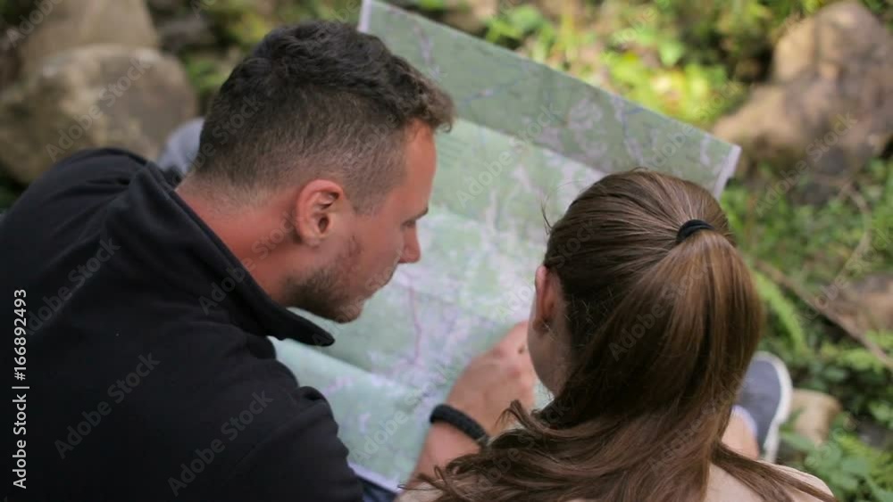 Young couple hikers in the woods looking for the road map Young couple hikers in the woods looking for the road map