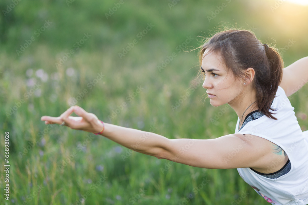 Yong indian woman doing yoga outdoor. Young woman exercising vital and meditation for fitness lifestyle at the nature background in green park on grass. Concept Yoga freedom