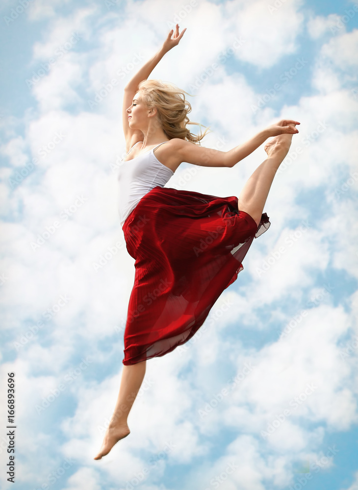 Fototapeta premium Beautiful passionate female dancer outdoors against blue sky