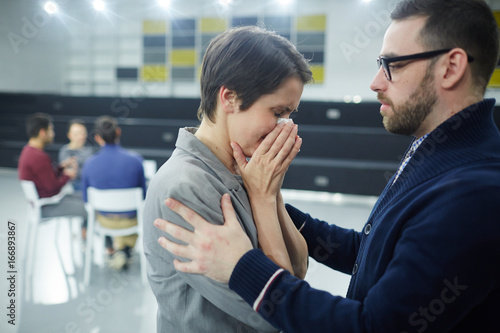 Stressed woman crying while colleague or groupmate comforting her