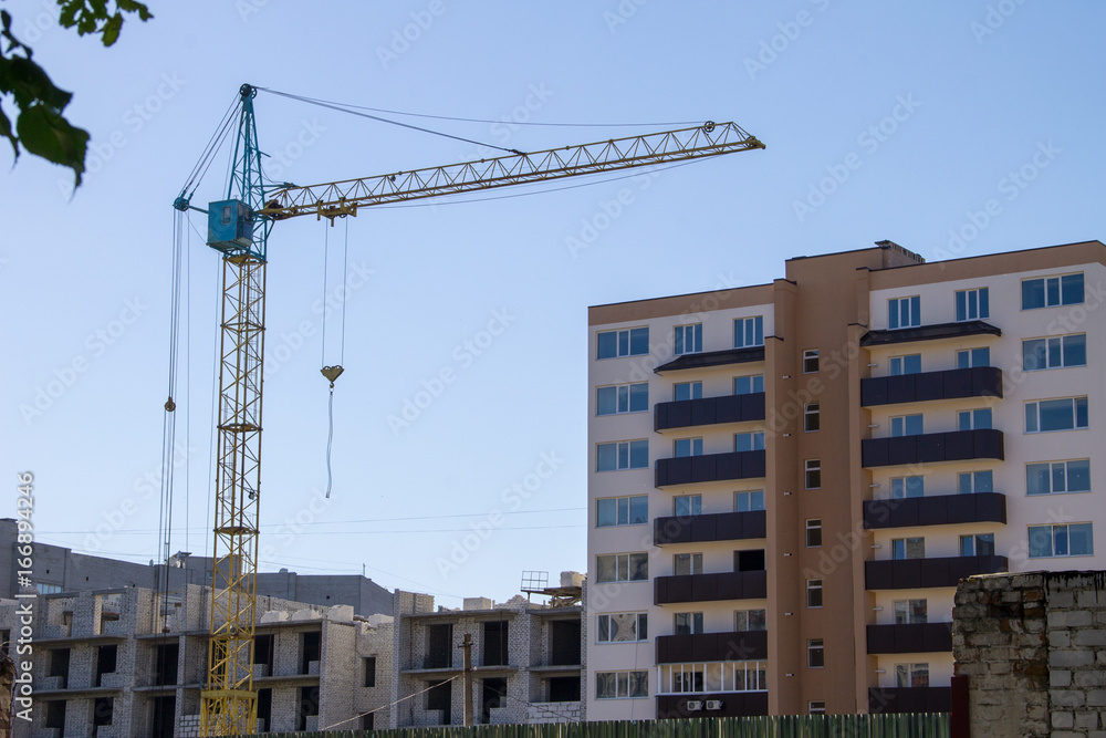 Building crane and building under construction against blue sky Building crane and building under construction against blue sky