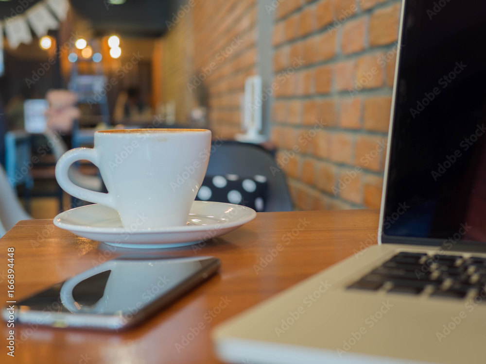 Laptop phone and coffee cup on table in cafe Laptop phone and coffee cup on table in cafe