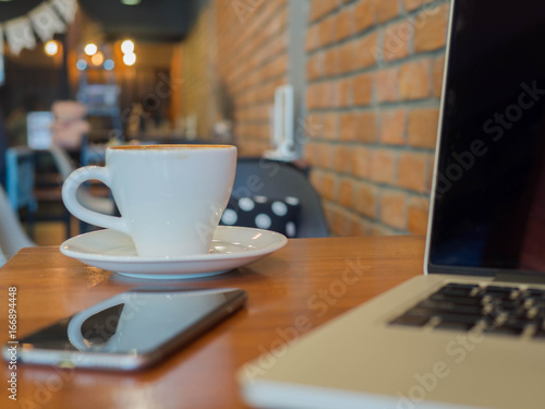 Laptop phone and coffee cup on table in cafe