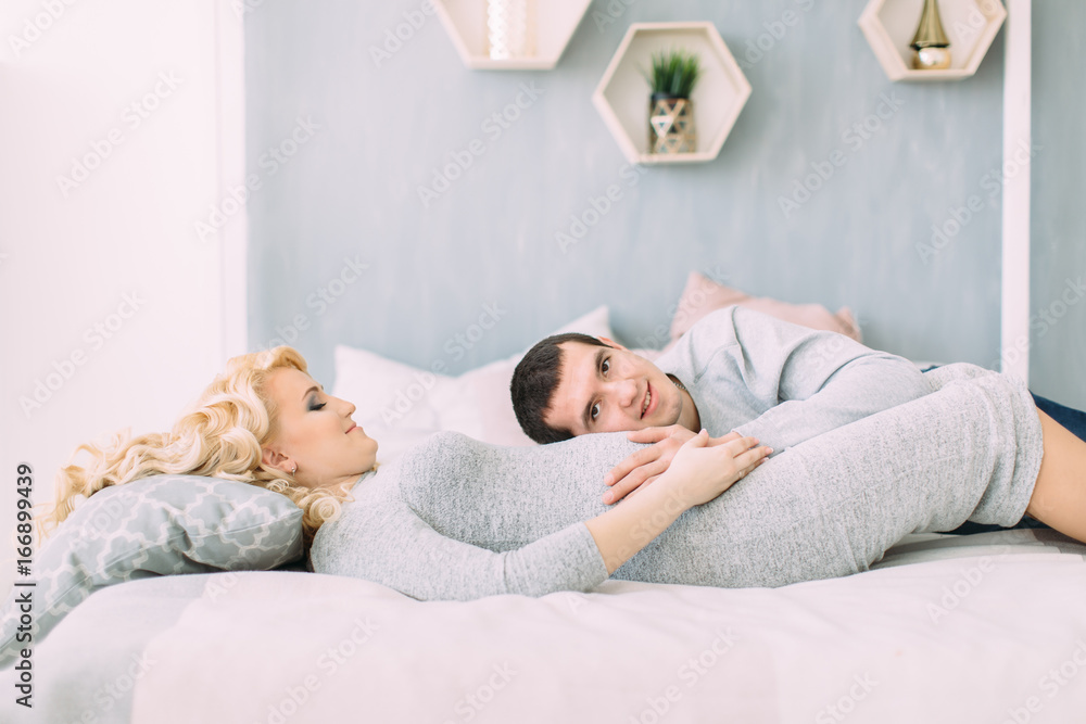 Pregnant girl with her husband lying on bed Pregnant girl with her husband lying on bed
