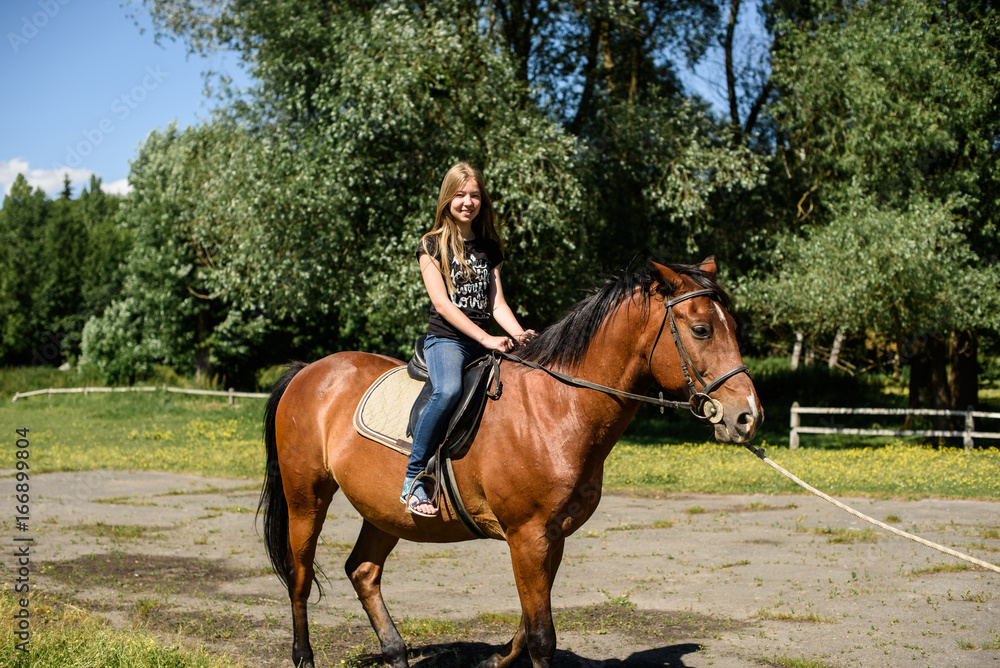 young beautiful brunette girl riding horse outdoor