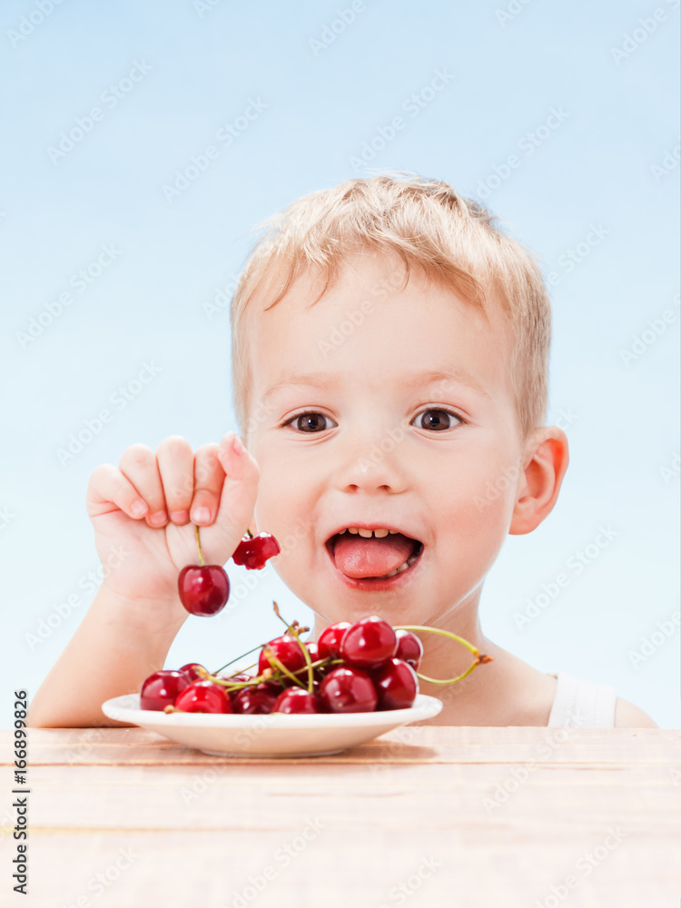 Child with red berries, boy eats and chooses cherry. Child with red berries, boy eats and chooses cherry.