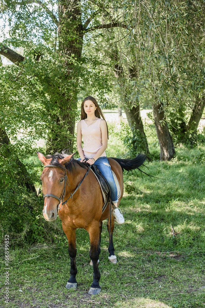 young beautiful brunette girl riding horse in park