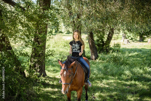 young beautiful brunette girl riding horse outdoor © Nestyda