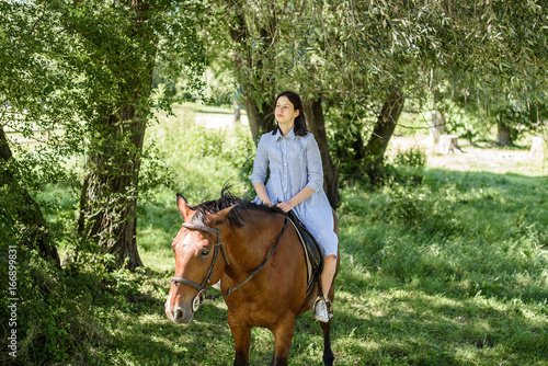 young beautiful brunette girl riding horse outdoor © Nestyda