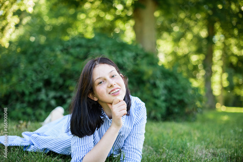 pretty brunette young woman lying on the grass, resting in the park on the weekend