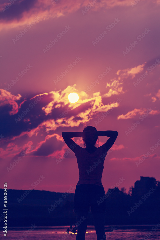 Silhouette of a young woman in the backdrop of the setting sun