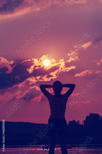 Silhouette of a young woman in the backdrop of the setting sun