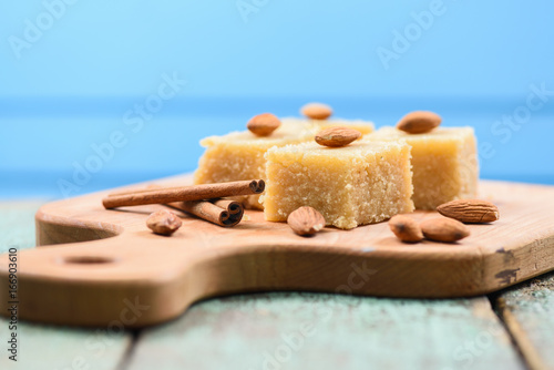 Foto Indian traditional dessert, halva wih cinnamon and almonds served on wooden boar