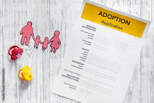 Adoption application near paper silhouette of family on light wooden table background top view photo