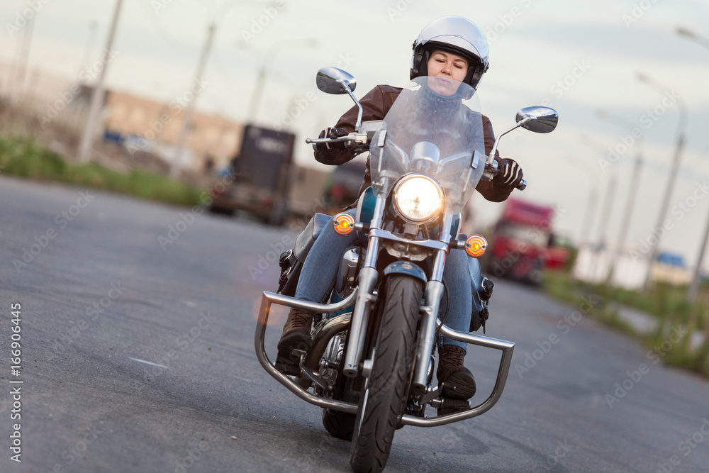 Front view at the moving motorcycle with young women motorcyclist, chrome chopper driving on road Front view at the moving motorcycle with young women motorcyclist, chrome chopper driving on road