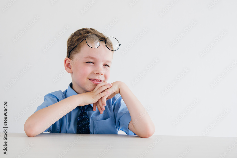 Schoolboy in school uniform and glasses sitting at the Desk Schoolboy in school uniform and glasses sitting at the Desk