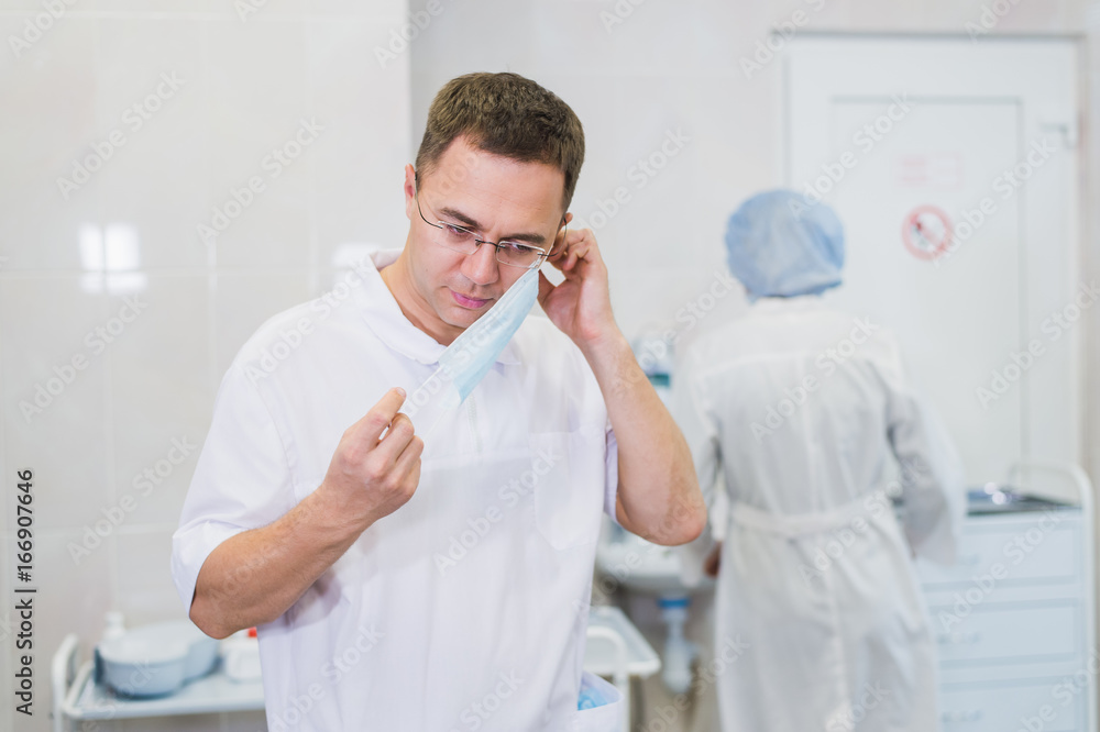 Thoughtful male surgeon wearing surgical mask in hospital Thoughtful male surgeon wearing surgical mask in hospital