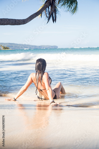 Junge Frau die an einem Karibikstrand sitzt photo