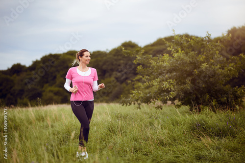 Glückliche schlanke Frau läuft durch ein Feld
