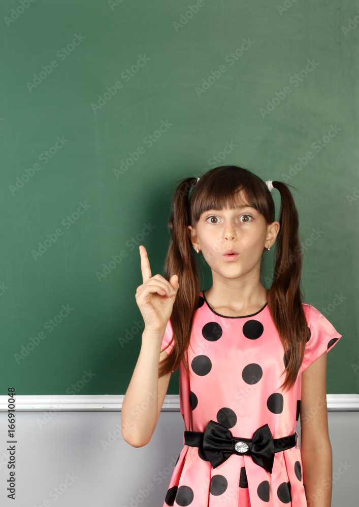 surprised child girl show with a finger empty school blackboard, copy space surprised child girl show with a finger empty school blackboard, copy space
