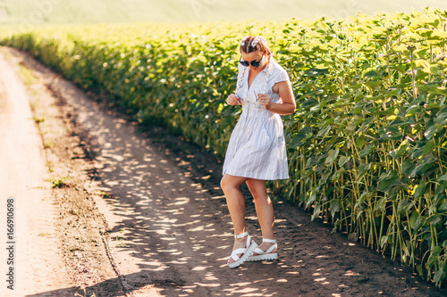 Portrait of young woman in a white dress against a background of green field photo