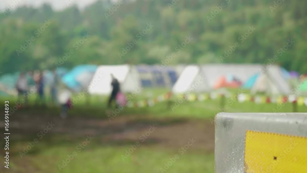 Blur of tent camp with people walking near it Blur of tent camp with people walking near it