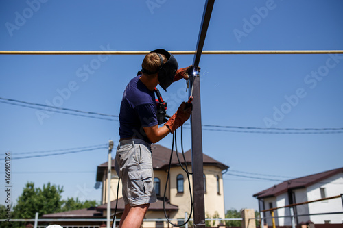 Man welding metal construction at his backyard. © Maksim Kostenko