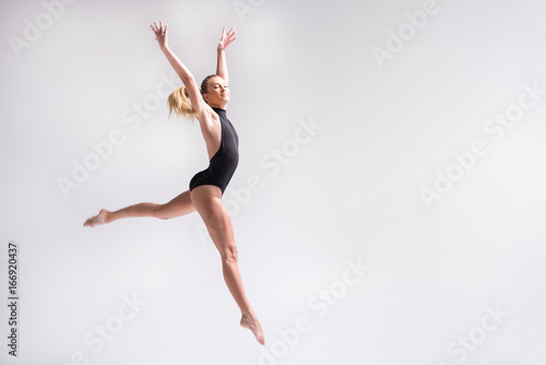 Sublime youthful lady performing gymnastics choreography jump