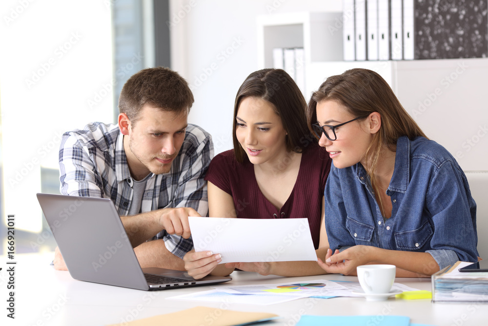 Coworkers working at office comparing data Coworkers working at office comparing data